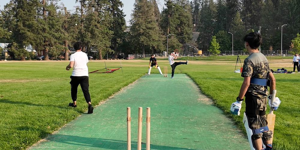 Students playing cricket in a park.