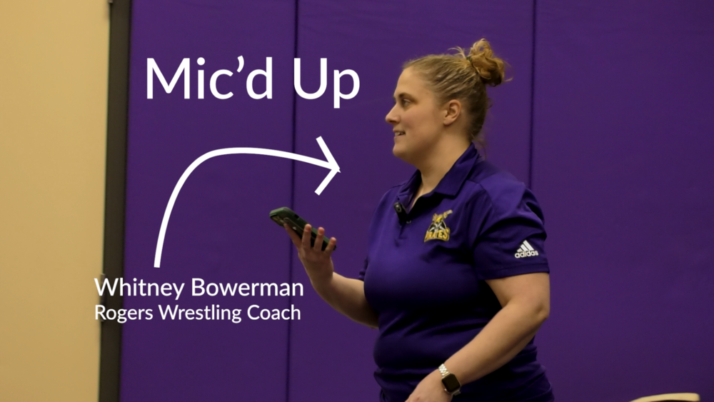 Rogers girls wrestling coach Whitney Bowerman holds a phone during practice. Text is “Mic’d Up.”