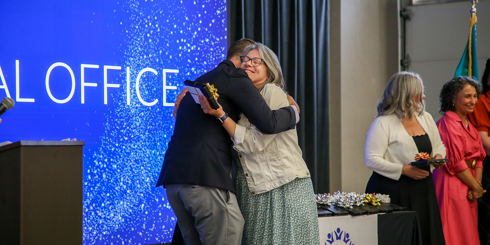 A Spokane Public Schools retiree hugs the superintendent and receives a retirement gift.