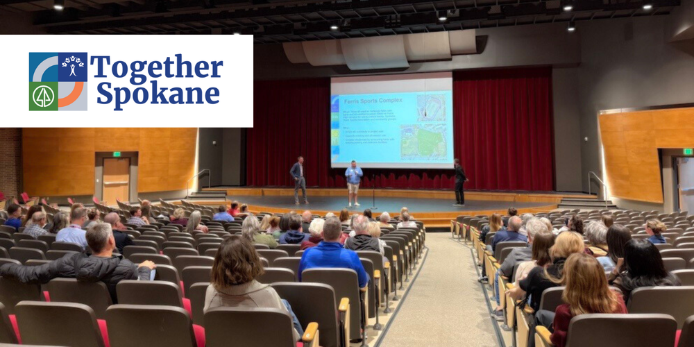 Three people on a stage share a presentation to people in an auditorium with the logo for Together Spokane.