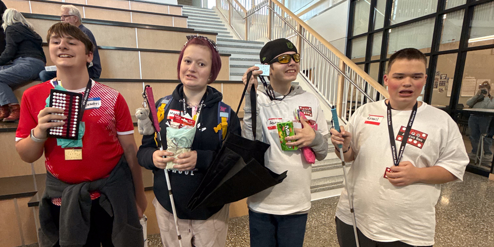 Four blind and visually impaired students pose for a group photo with their medals and prizes for a competition.