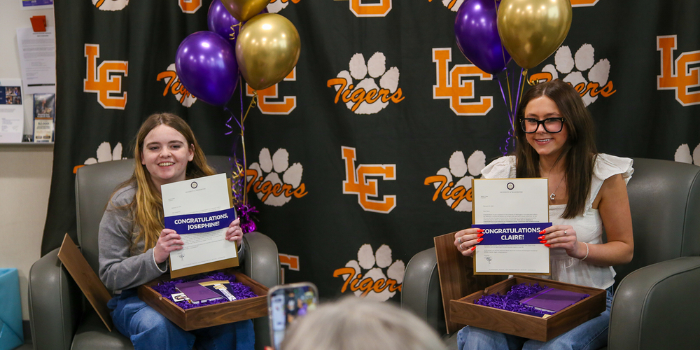 Lewis & Clark High School seniors Josephine Corbin and Claire Poulsen smile while holding acceptance gifts to the University of Washington.