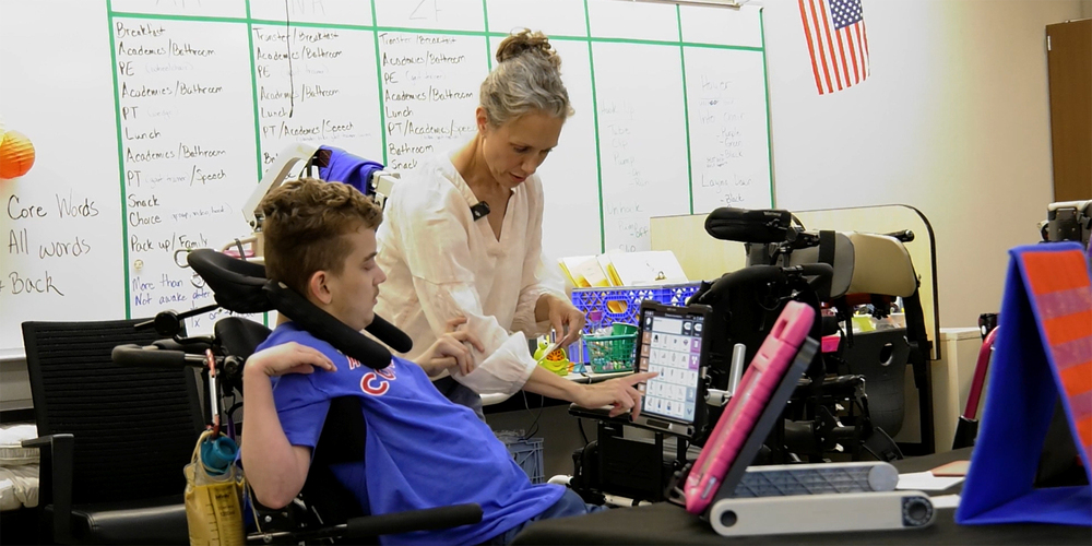 A Special Education teacher helps student in a classroom.