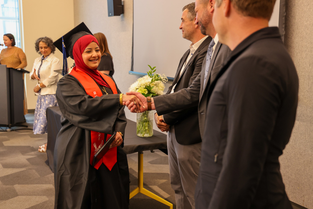 Spokane Virtual graduates shake hands as they receive a diploma.
