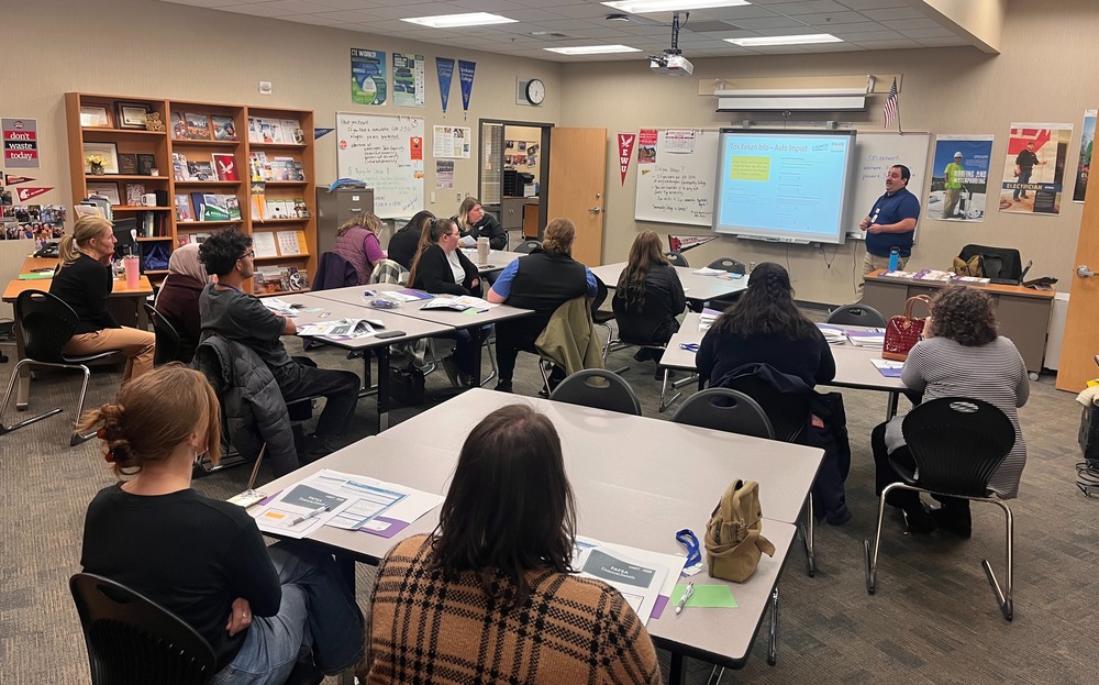 A group of adults sit in a career counseling office, listening to a presenter.