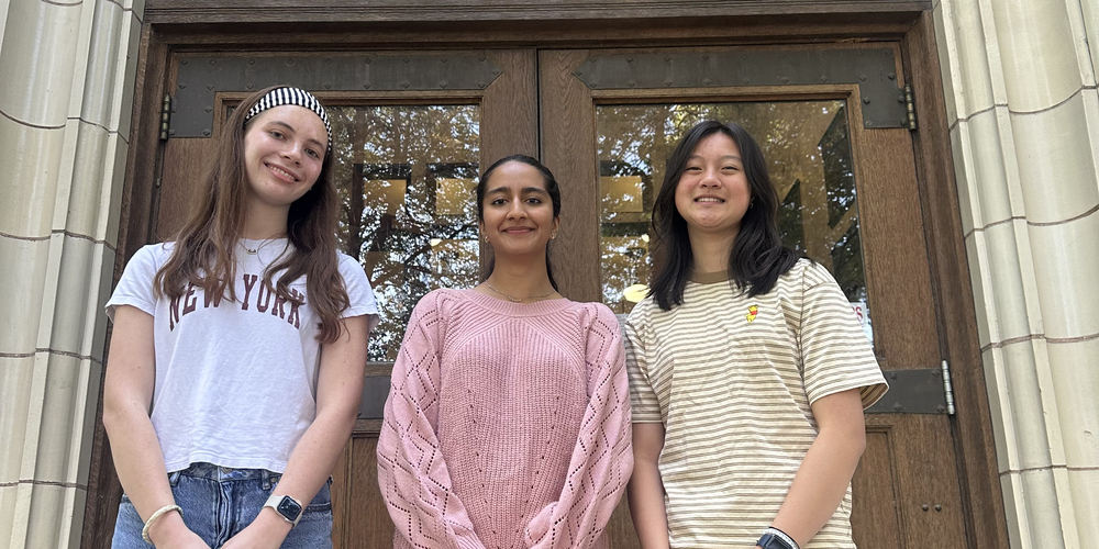 Three high school seniors pose in front of their school