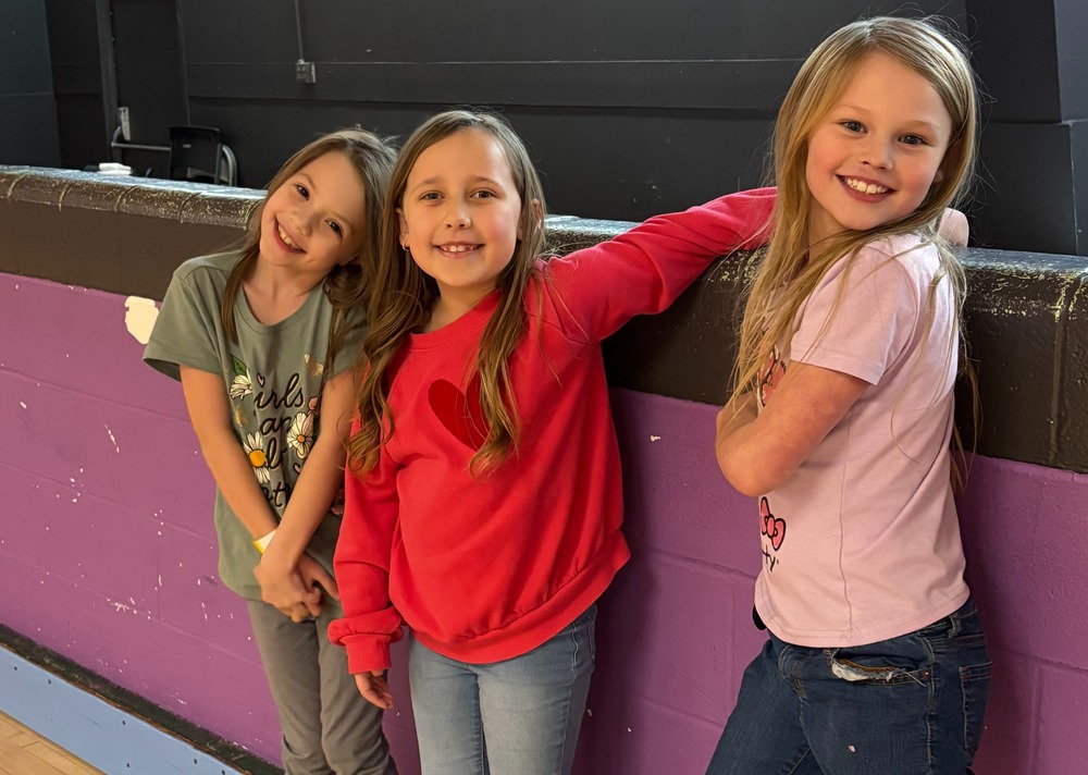 Children smiling at skate rink.