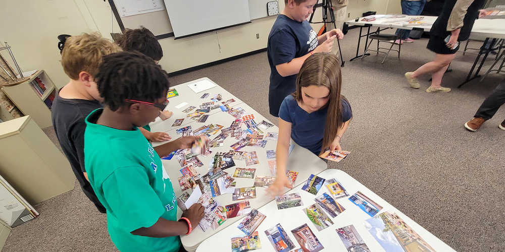 Elementary students pick from assorted photographs to help display their design ideas for a new school.