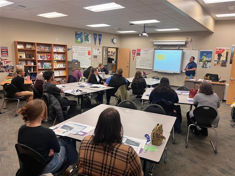 A group of adults sit in a career counseling office, listening to a presenter.