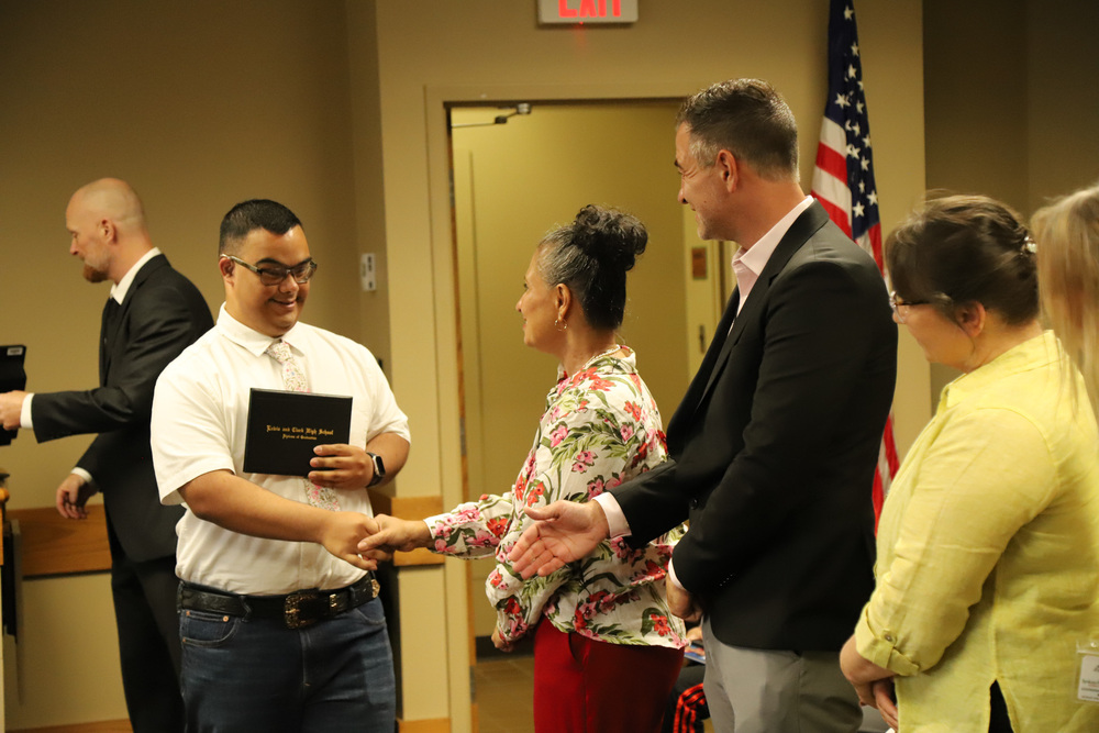 A Secondary Transition student shakes hands with staff after receiving their diploma.