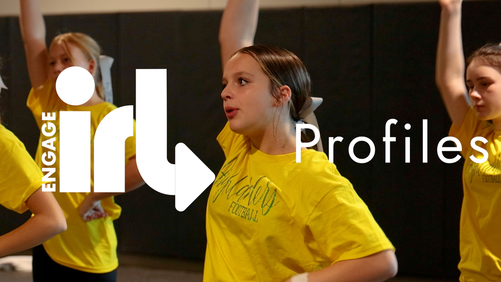A student in a yellow shirt practices cheerleading. The text Enage IRL Profiles is on screen.