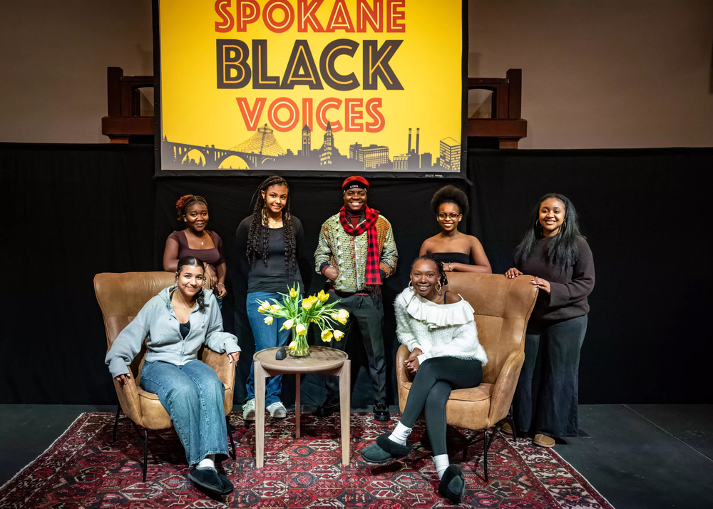 Seven Black teenagers pose on a stage under a banner for Spokane Black Voices.