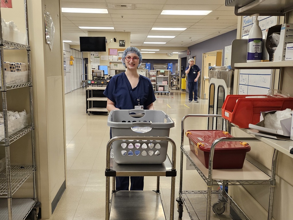 Student pushing a cart of medical equipment during an internship experience.