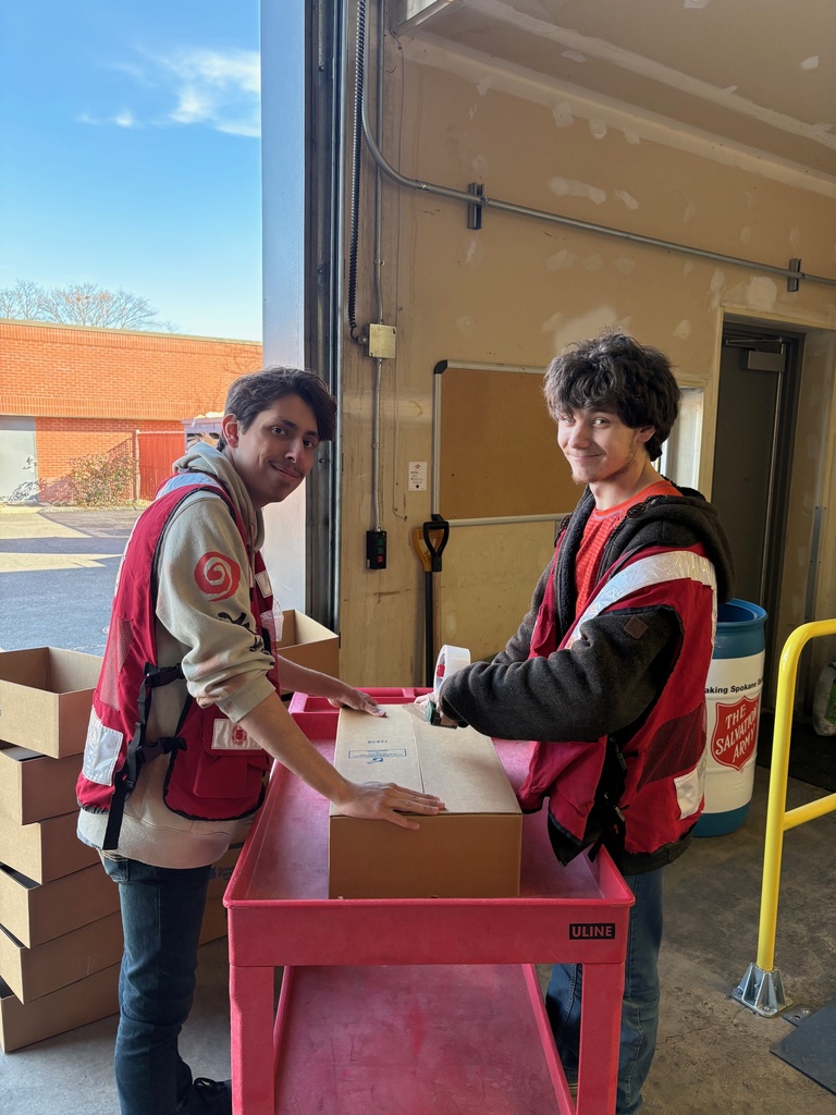 Two students at the Salvation Army Food Bank working on unboxing items.