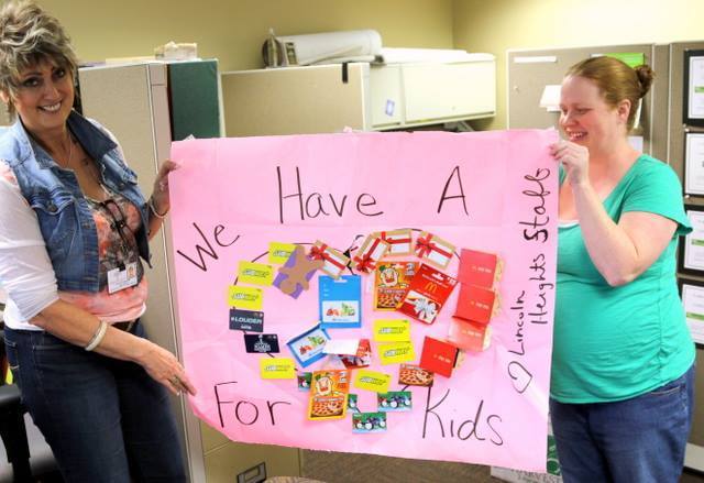 Two women smiling holding a poster with gift cards attached and the message "We have a heart for kids, Love, the Lincoln Heights Staff."