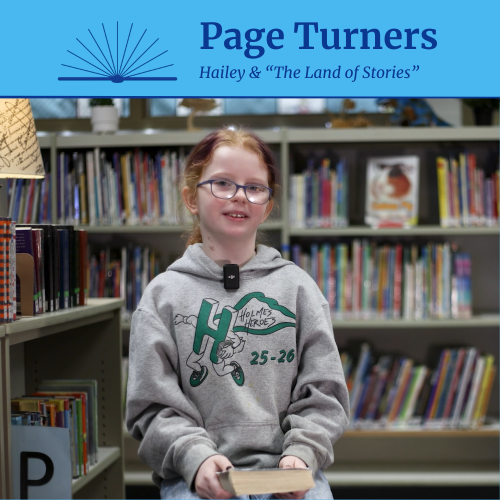 Holmes Elementary School student Hailey sits in a library to recommend the book The Land of Stories for the Page Turners video series.