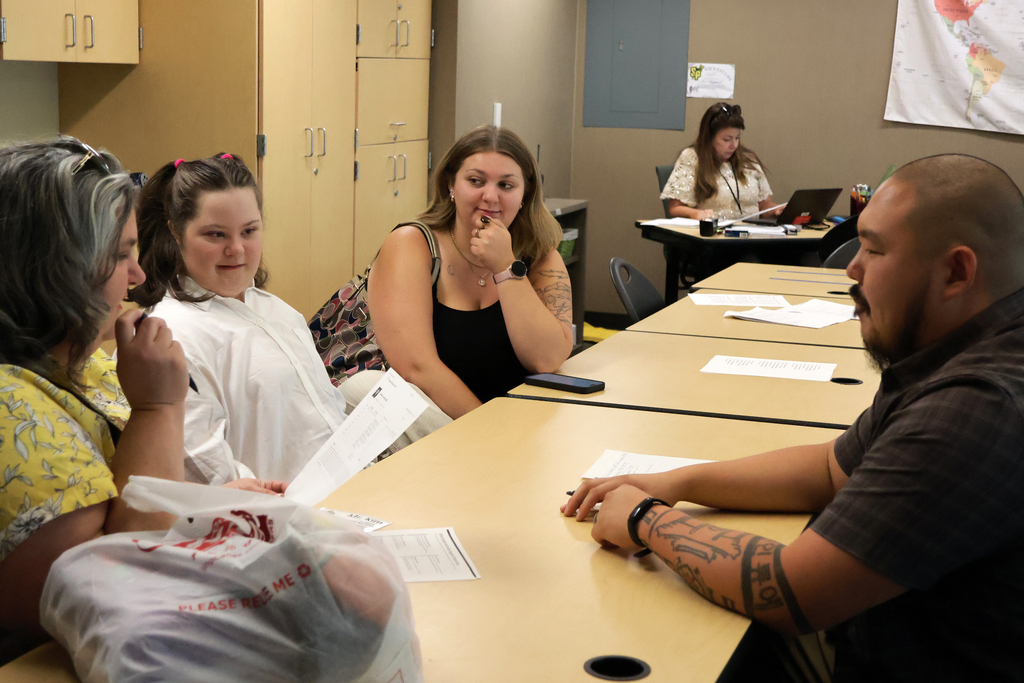 A family meets with a high school teacher for a conference.