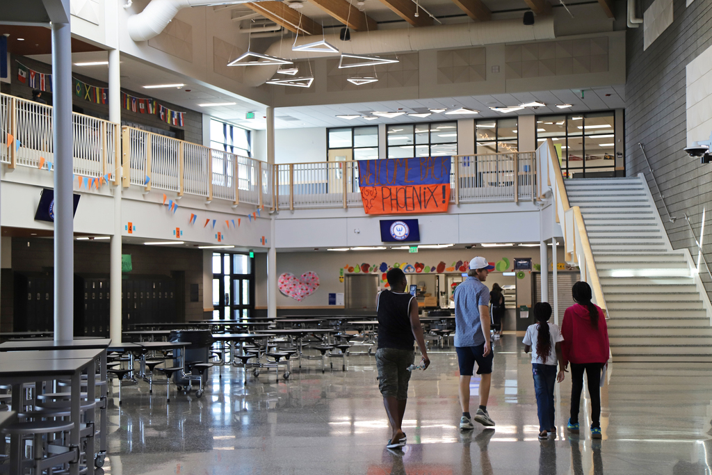 A middle school family walks through their school; a banner reading "Welcome Back Phoenix" hangs above them.