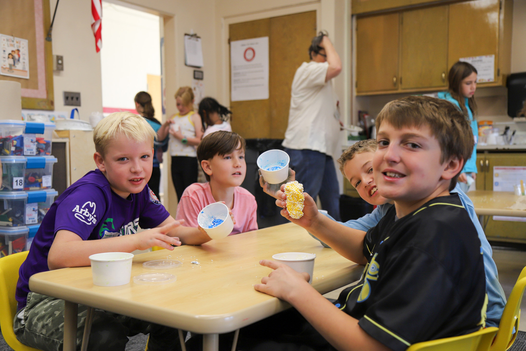 Elementary students show off the homemade slime and floam they made in a classroom.