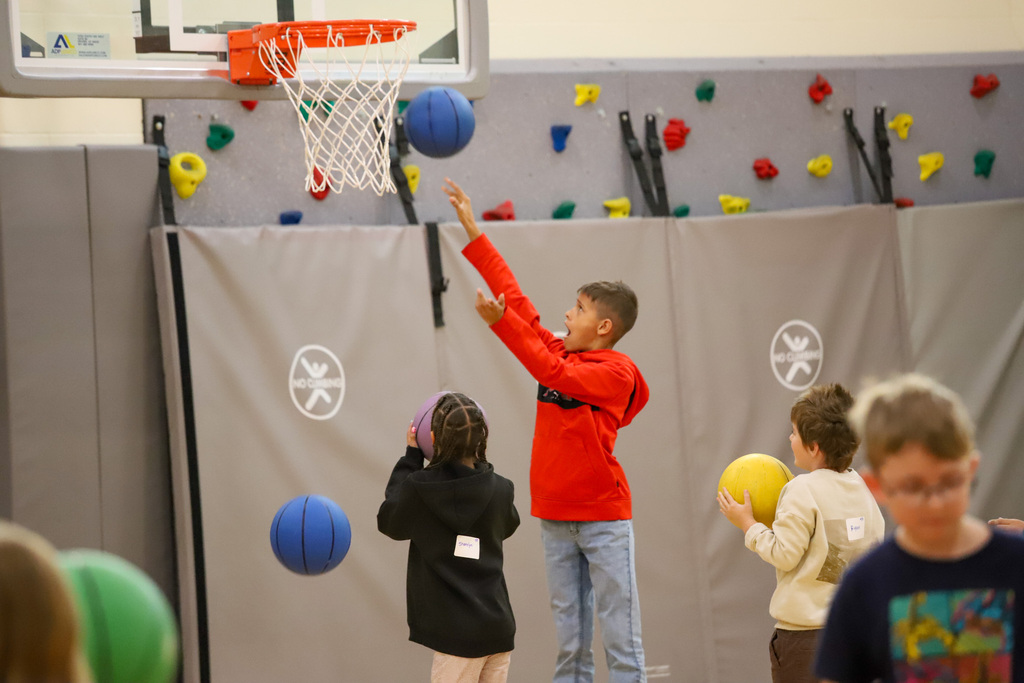 Elementary students play basketball in a school gym.