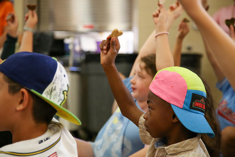 Jefferson elementary students hold up wooden hearts during an assembly.