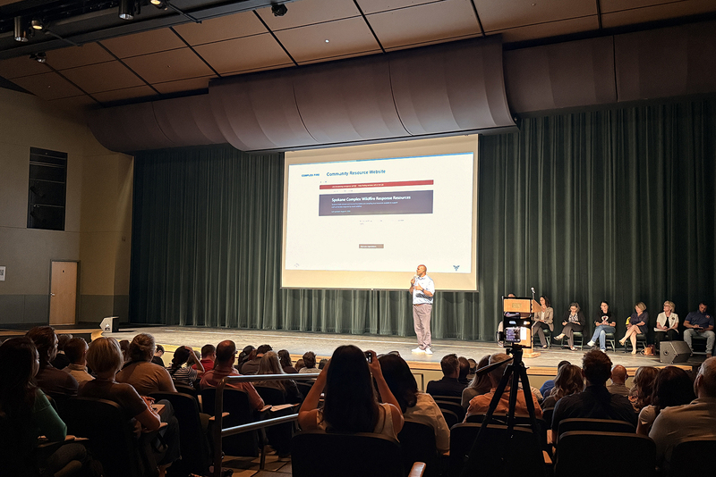 Dr. Oscar Harris speaks on stage to an auditorium of community organization leaders.