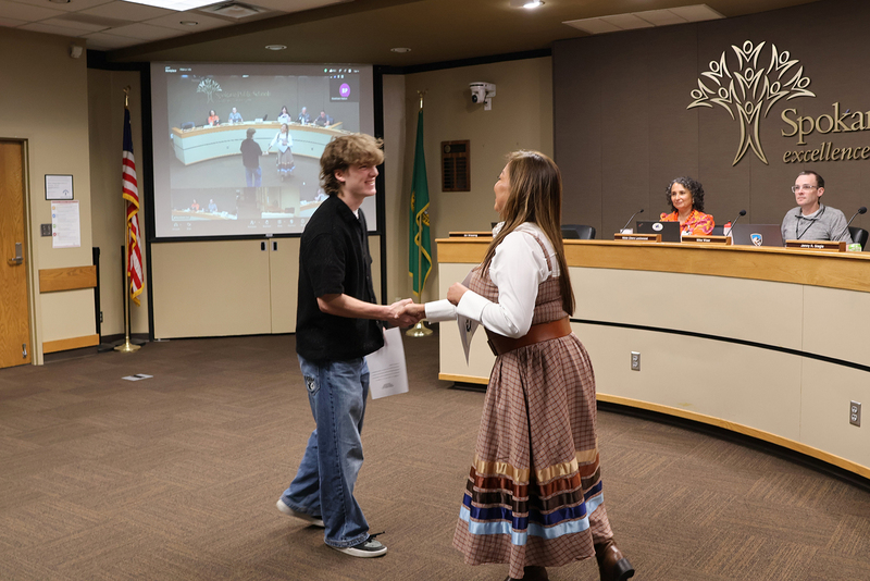 School Board president Jenny Slagle shakes hands with student advisor Eli Wissing.