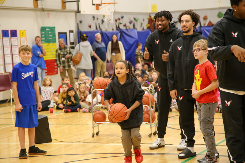 Elementary students play basketball with college student athletes.