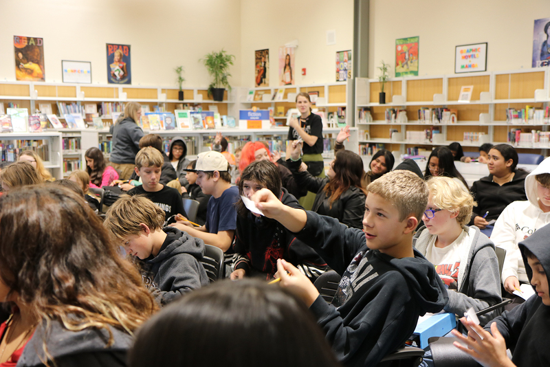 Shaw middle school students raise their hands during an election education program.