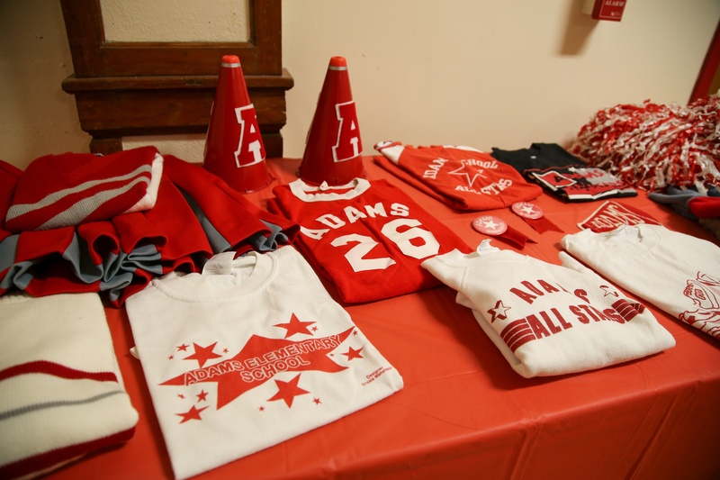 A table with red and white Adams Elementary memorabilia.