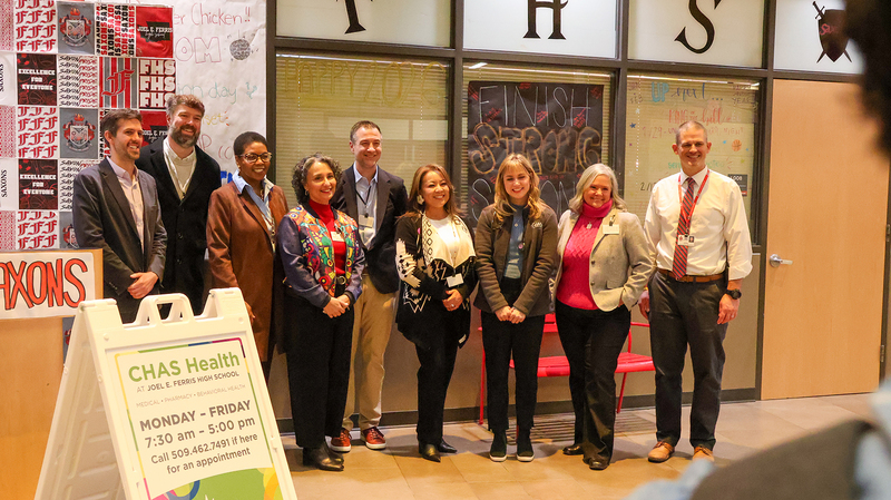 Spokane Public Schools, City of Spokane, and CHAS Health leaders smile in front of the new school-based health clinic inside Ferris High School.