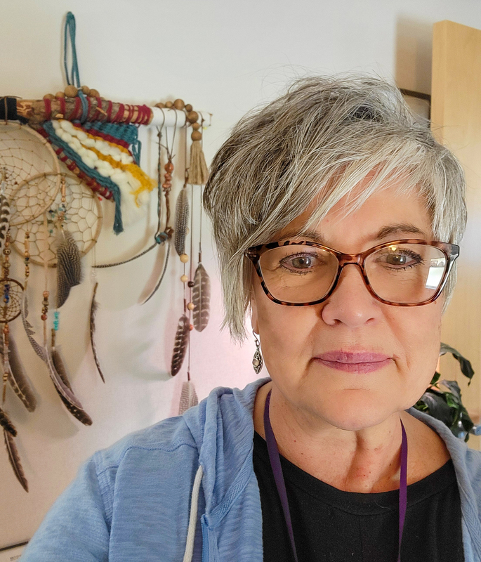 Woman standing in front of Native American art. Lori Beatty.