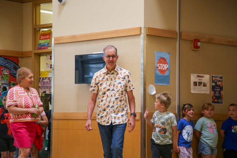 Man leading group of children through elementary school hallway. Tom Voigt.