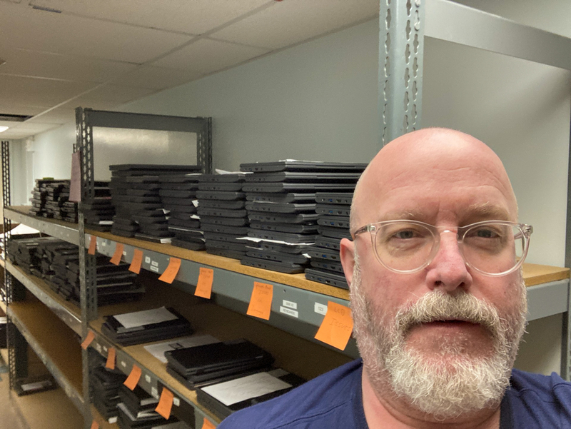 Man standing in front of racks of laptops. Chris Lougheed.