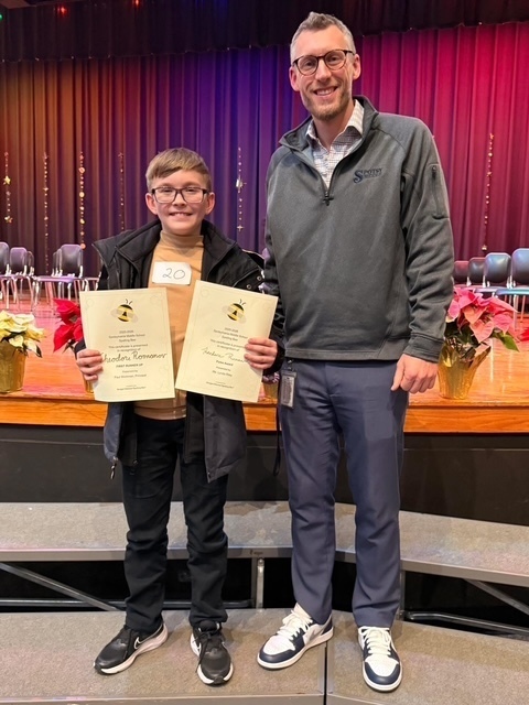 principal is standing with student holding his certificates