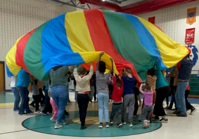 Students playing with the parachute in the gym