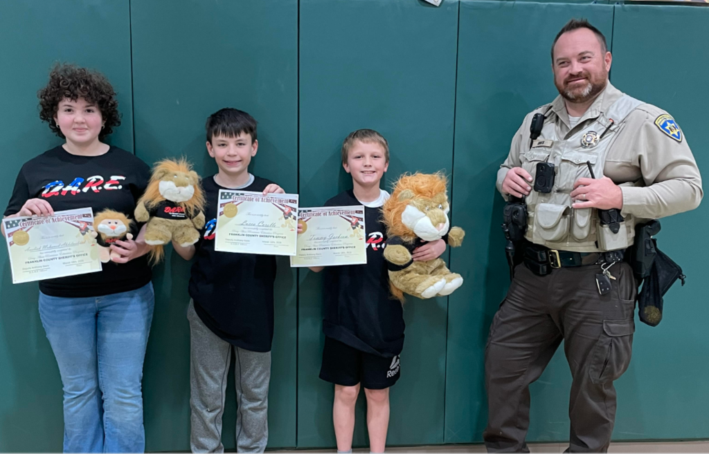 DARE Essay winners (left to right) Ameilah, 3rd place, Lucca C., 2nd place, and Tommy, 1st place. Also pictured Deputy Davis, DARE Instructor
