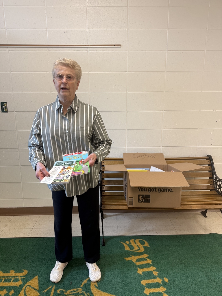 A lady holding books donated by Mr. Rif's Readers. 