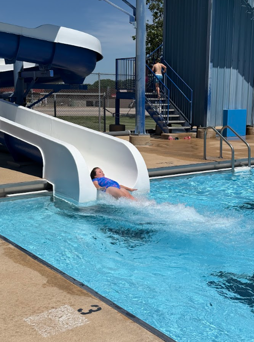 student coming down the slide at the pool