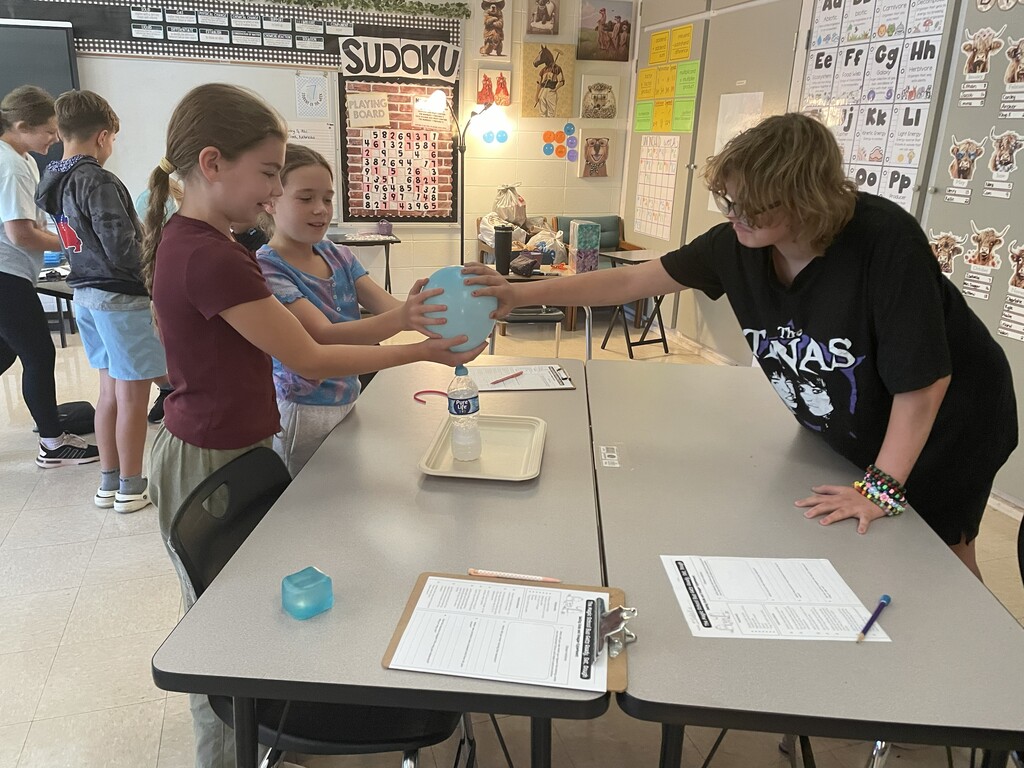 Students observing a balloon blowing up due to gases being produced by a chemical reaction.