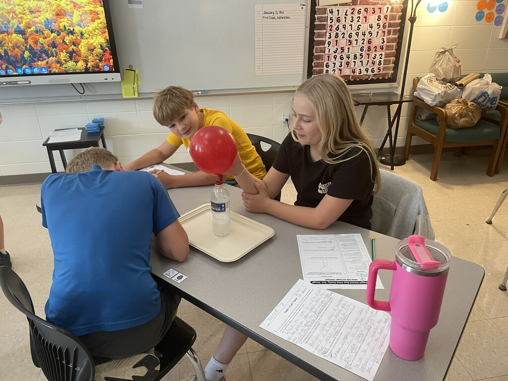 Students observing a balloon blowing up due to gases being produced by a chemical reaction.
