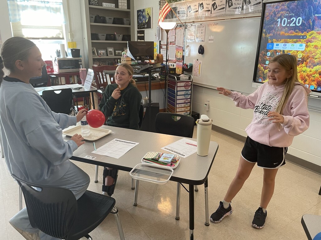 Students observing a balloon blowing up due to gases being produced by a chemical reaction.