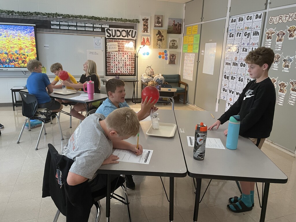 Students observing a balloon blowing up due to gases being produced by a chemical reaction.