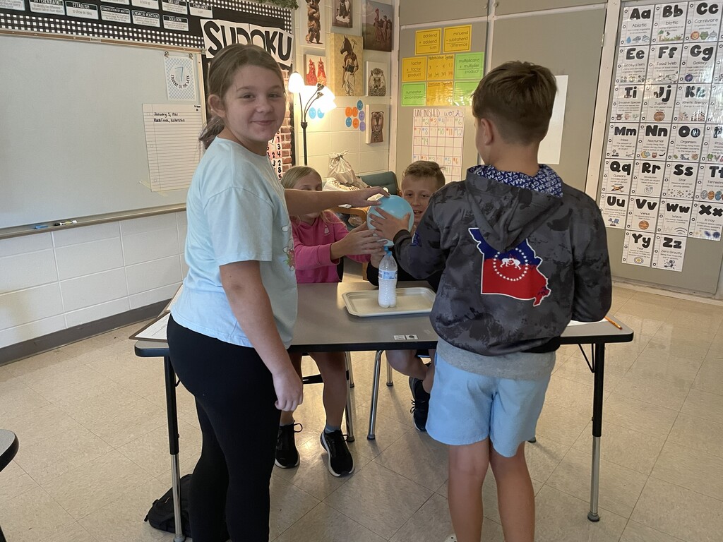 Students observing a balloon blowing up due to gases being produced by a chemical reaction.