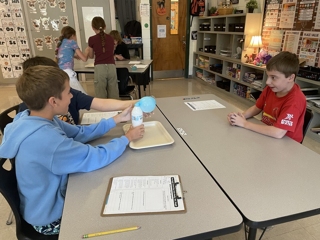Students observing a balloon blowing up due to gases being produced by a chemical reaction.