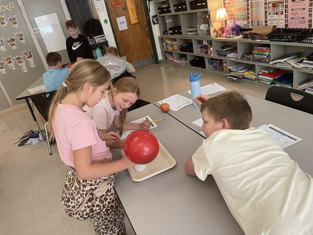Students observing a balloon blowing up due to gases being produced by a chemical reaction.