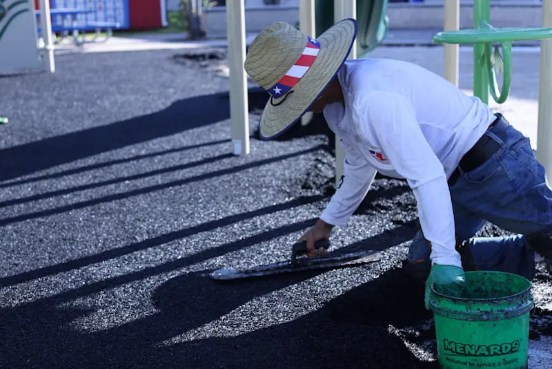 man putting tar down on a playground