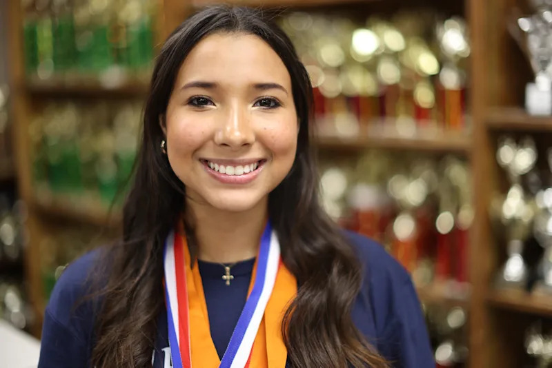 Nina Skae wearing a medal in front of a trophy wall