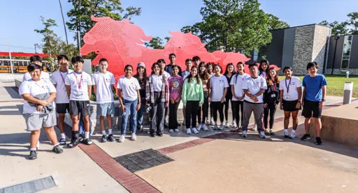 group of students posed in front of memorial high school horse sculpture
