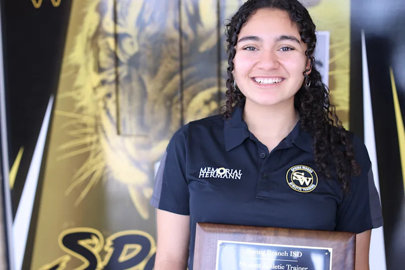 Aylin Castaneda-Galvan smiling and holding a plaque reading "Student Athletic Trainer"